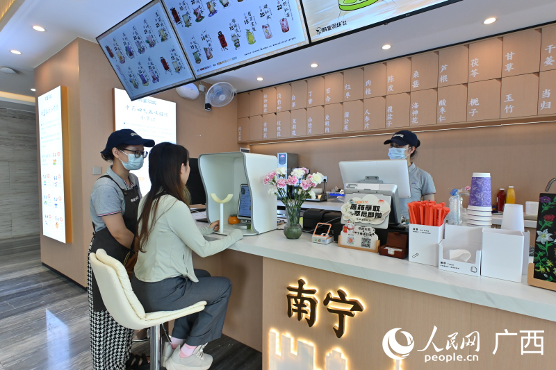 韦女士在店员的指导下使用AI配制中药茶饮。人民网 雷琦竣摄